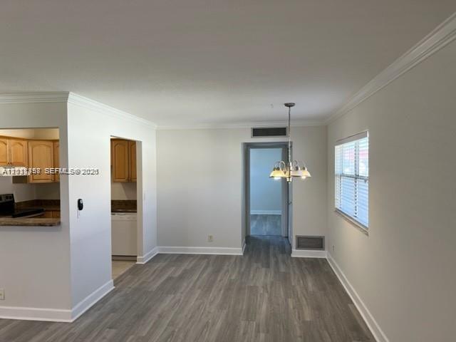 A dining area with wood-look flooring, a chandelier, and an adjacent kitchen — 594 Saxony M # 594, Delray Beach FL 33446, DELRAY BEACH, FL