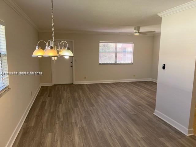 An open-concept dining and living area features light wood-look flooring and a hanging chandelier — 594 Saxony M # 594, Delray Beach FL 33446, DELRAY BEACH, FL