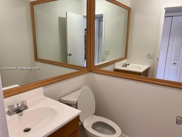 A bathroom features a white pedestal sink, a toilet, and large mirrors with wood frames — 594 Saxony M # 594, Delray Beach FL 33446, DELRAY BEACH, FL