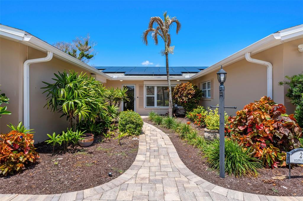 A stone walkway leads to the entrance of a house with solar panels on the roof — 27 WESTVIEW LANE, COCOA BEACH, FL