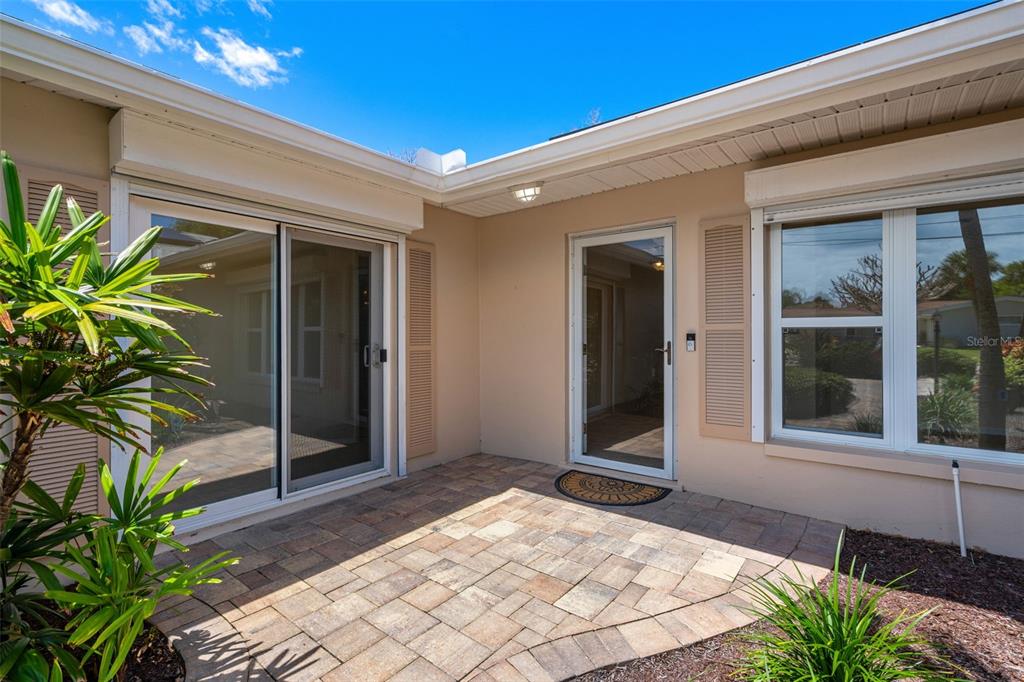 A paved patio area sits between a sliding glass door and a front entry door — 27 WESTVIEW LANE, COCOA BEACH, FL
