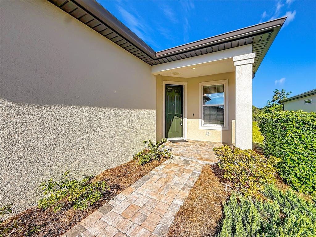 A paved walkway leads to the front entrance of a house with a green door — 6046 SW 93RD CIRCLE, OCALA, FL
