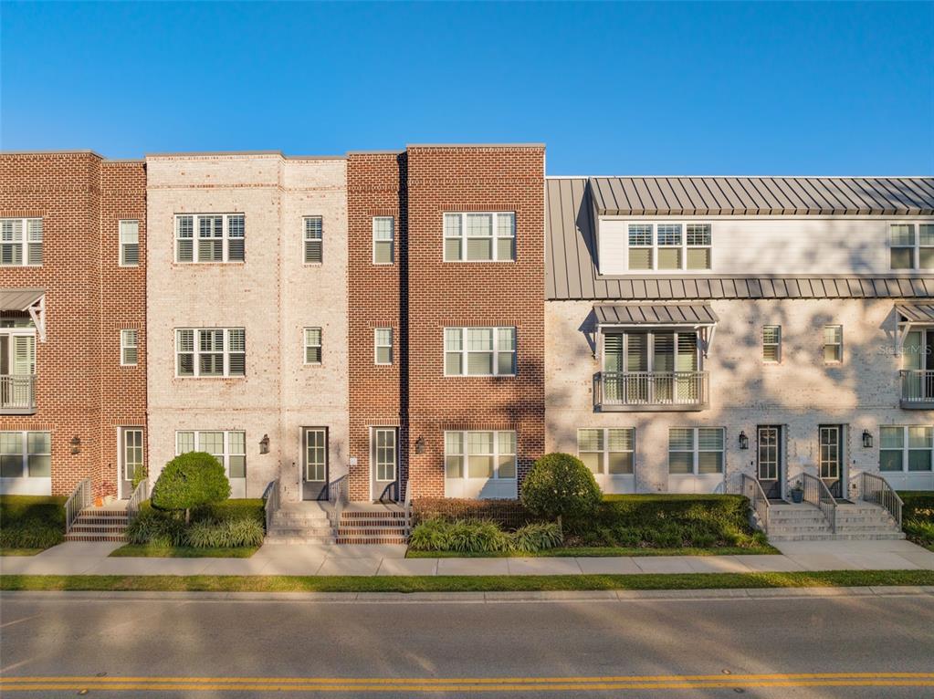 A row of three-story brick townhomes with balconies and sidewalks along a street — 129 S PARK AVENUE, WINTER GARDEN, FL