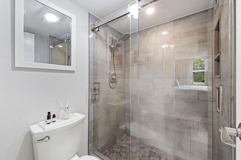 A bathroom features a glass-enclosed shower with pebble flooring and gray wall tiles — 3801 Environ Boulevard # 318, Lauderhill FL 33319, LAUDERHILL, FL