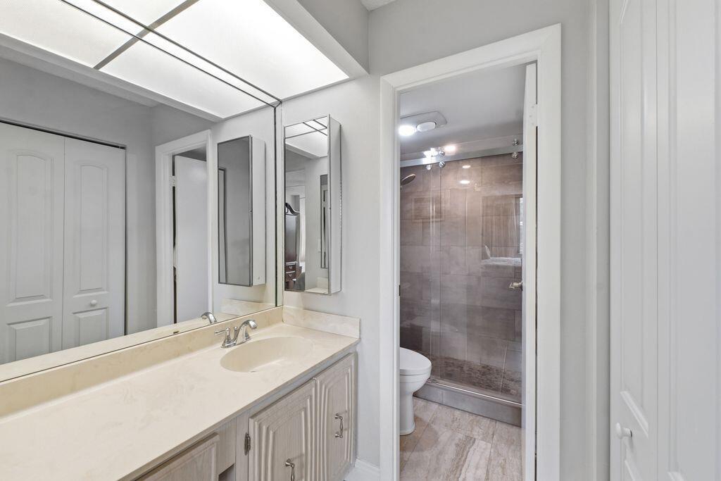 A bathroom features a vanity with a light countertop, a large mirror, and a shower — 3801 Environ Boulevard # 318, Lauderhill FL 33319, LAUDERHILL, FL