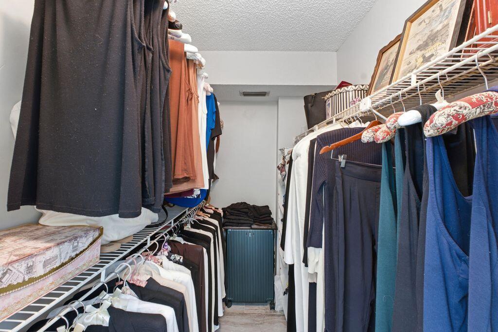 A walk-in closet features wire shelving, hanging clothes, and a suitcase on the floor — 3801 Environ Boulevard # 318, Lauderhill FL 33319, LAUDERHILL, FL