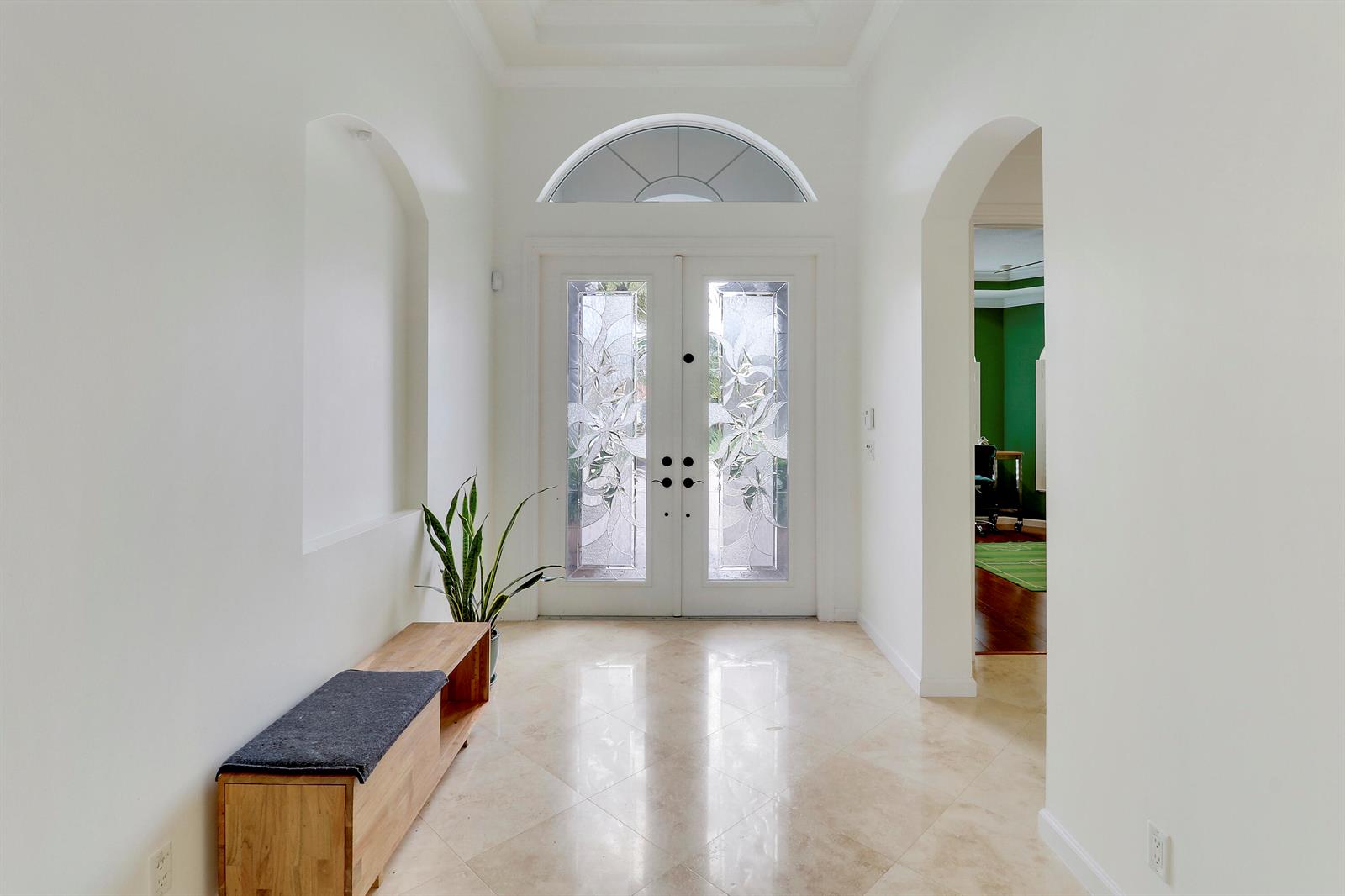 A bright entryway features a double glass door, arched alcove, wooden bench, and tile flooring — 236 Carina Drive, Jupiter FL 33478, JUPITER, FL