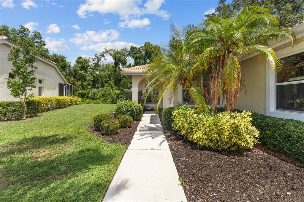 A concrete walkway leads to the entrance of a house with a palm tree — 6662 OAKBROOKE CIRCLE, BRADENTON, FL