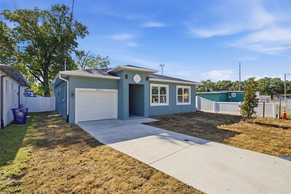 A single-story blue house with a white garage door and a concrete driveway — 4013 N 29TH STREET, TAMPA, FL