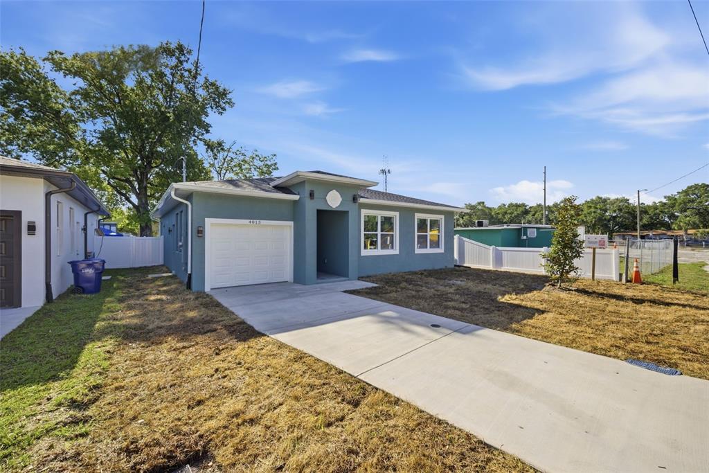 A teal, single-story house with a white garage door and a concrete driveway — 4013 N 29TH STREET, TAMPA, FL