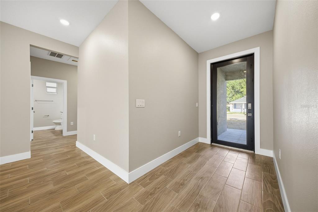 An entryway with wood-look tile flooring leads to a glass-paneled door and a bathroom — 4013 N 29TH STREET, TAMPA, FL