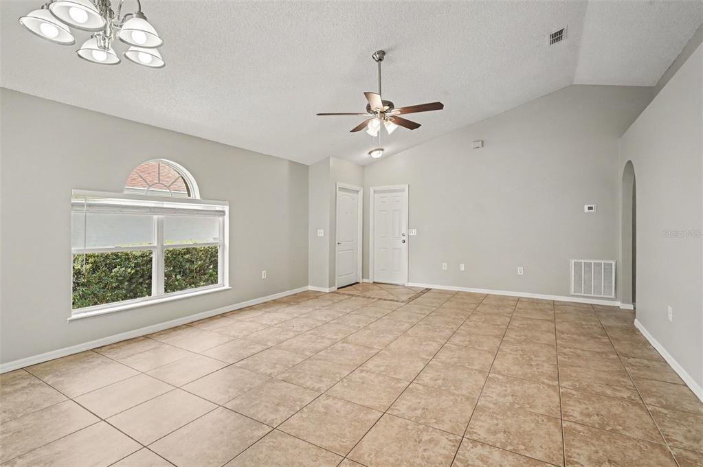 A spacious living room features light-colored walls, tile flooring, a ceiling fan, and arched windows — 5655 NEW CAMBRIDGE ROAD, ORLANDO, FL