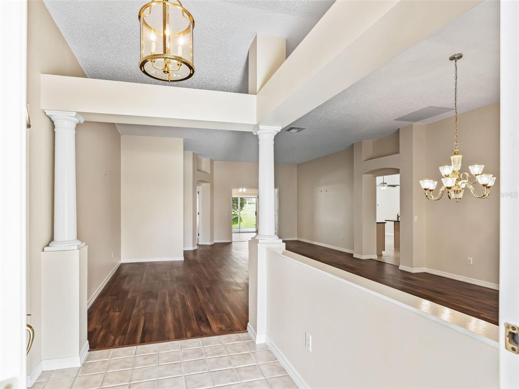 An entryway with tile flooring leads to a living area featuring wood floors and columns — 823 SAN SALVADOR DRIVE, THE VILLAGES, FL