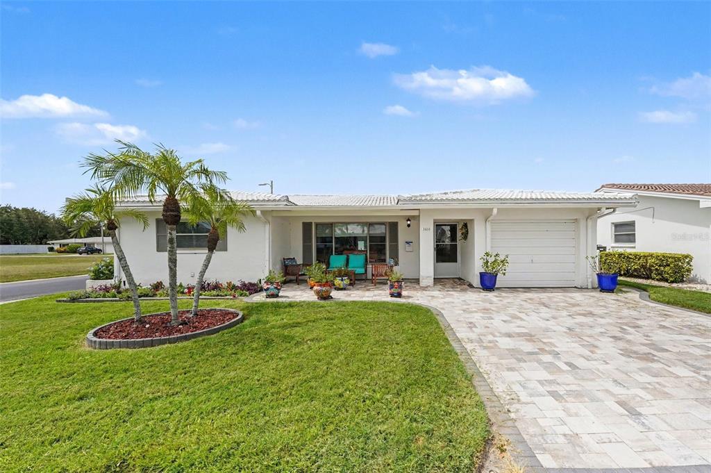 A single-story white house features a paved driveway, a front patio, and a palm tree — 3450 101ST TERRACE N, PINELLAS PARK, FL