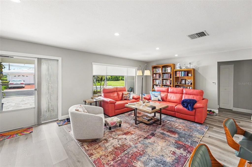 A living room features a red sofa, a white armchair, and a large patterned rug — 3450 101ST TERRACE N, PINELLAS PARK, FL