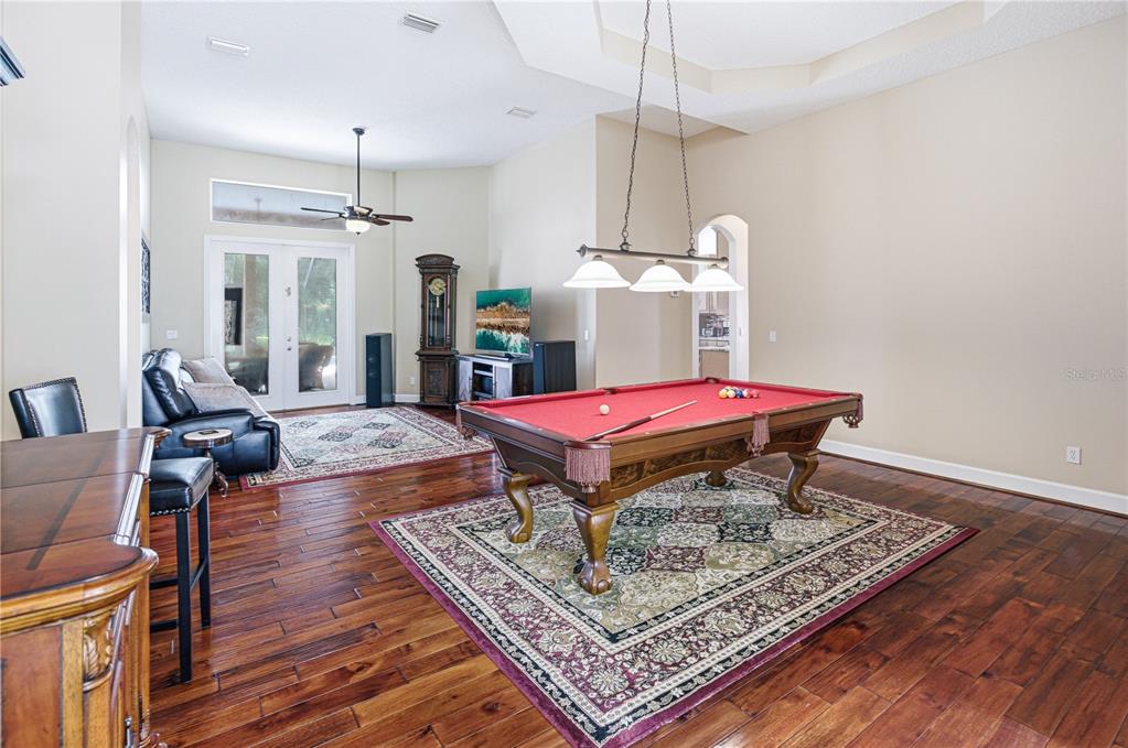 A spacious room features a red pool table, hardwood floors, and a seating area — 14473 MAGNOLIA SPRINGS LANE E, JACKSONVILLE, FL
