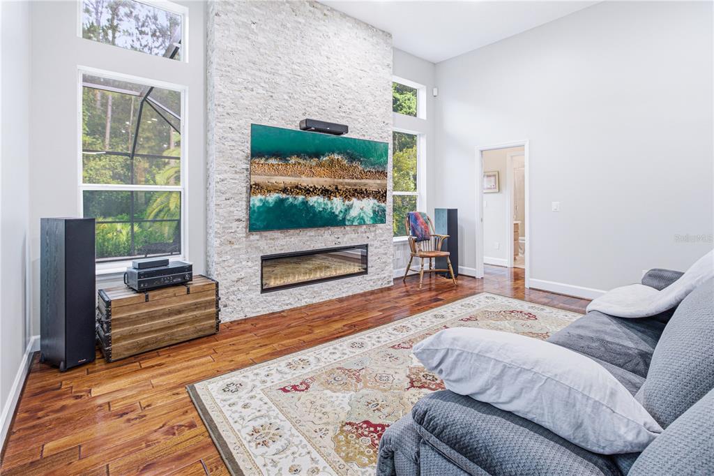 A living room features a stone fireplace, a wall-mounted television, and hardwood flooring — 14473 MAGNOLIA SPRINGS LANE E, JACKSONVILLE, FL