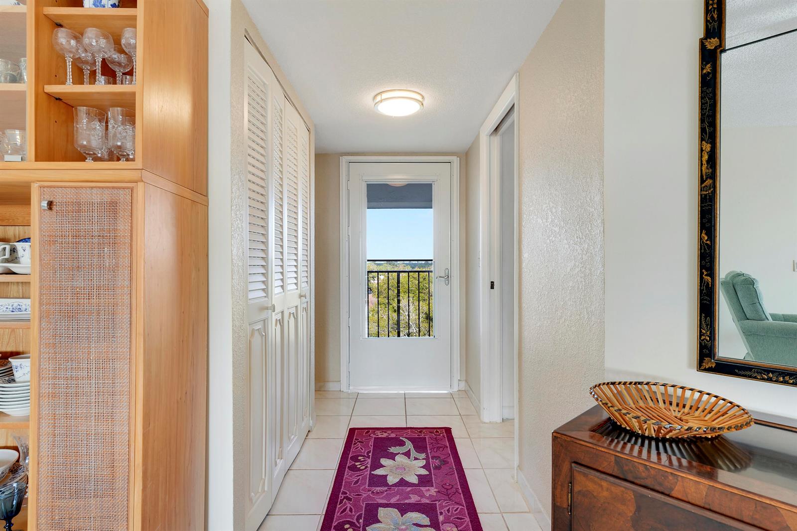 A hallway with white tile floors, louvered closet doors, and a glass door to a balcony — 3597 Birdie Drive # 607, Lake Worth FL 33467, LAKE WORTH, FL