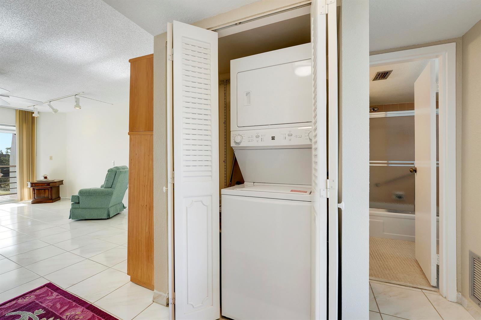 A stacked washer and dryer unit is housed in a closet between a living area and bathroom — 3597 Birdie Drive # 607, Lake Worth FL 33467, LAKE WORTH, FL
