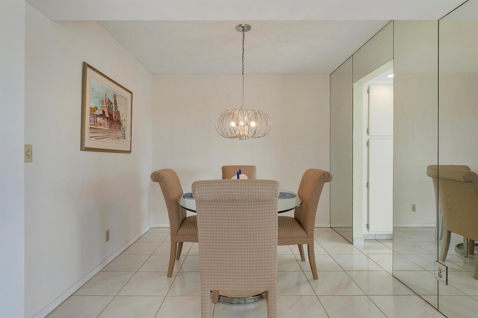 A dining room with a glass table, four wicker chairs, and a modern orb chandelier — 3597 Birdie Drive # 607, Lake Worth FL 33467, LAKE WORTH, FL