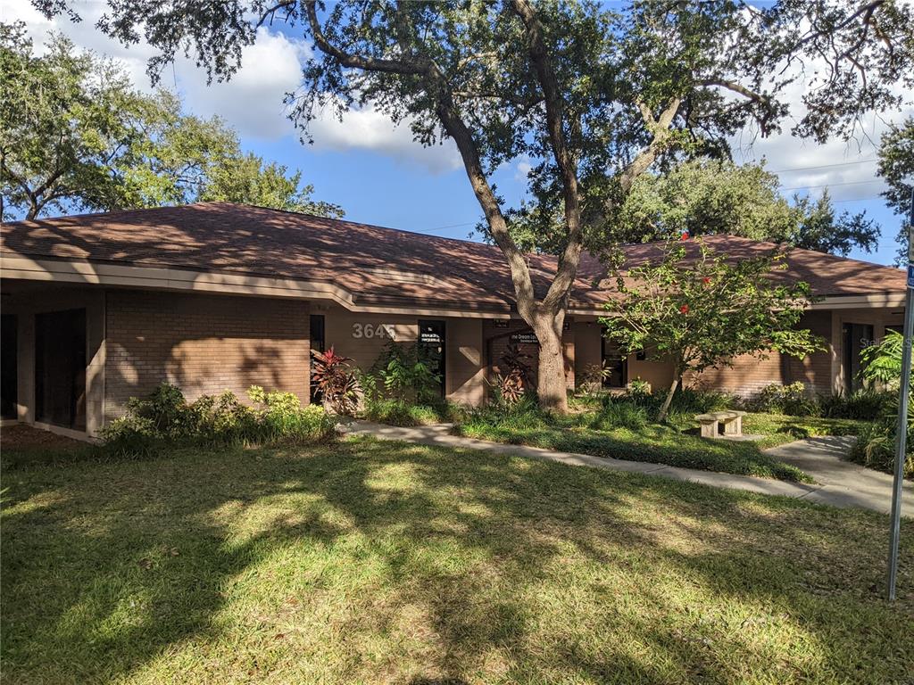 A single-story brick commercial building with a brown shingled roof and mature trees — 3655 CORTEZ ROAD W UNIT 120, BRADENTON, FL