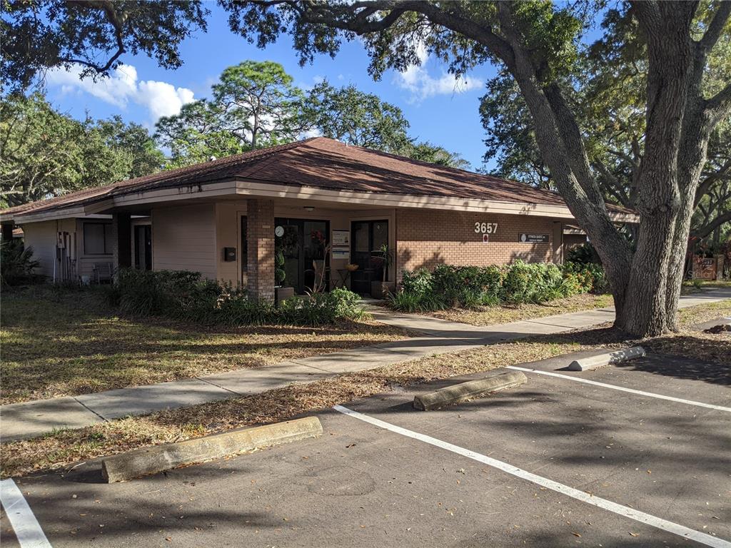 A single-story commercial building with a brick facade, brown roof, and surrounding trees — 3655 CORTEZ ROAD W UNIT 120, BRADENTON, FL