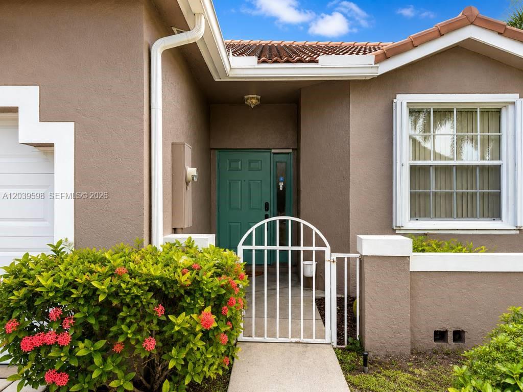 The exterior of a house features a green front door, a white gate, and landscaping — 8090 S Aragon Blvd # 3, Sunrise FL 33322, SUNRISE, FL