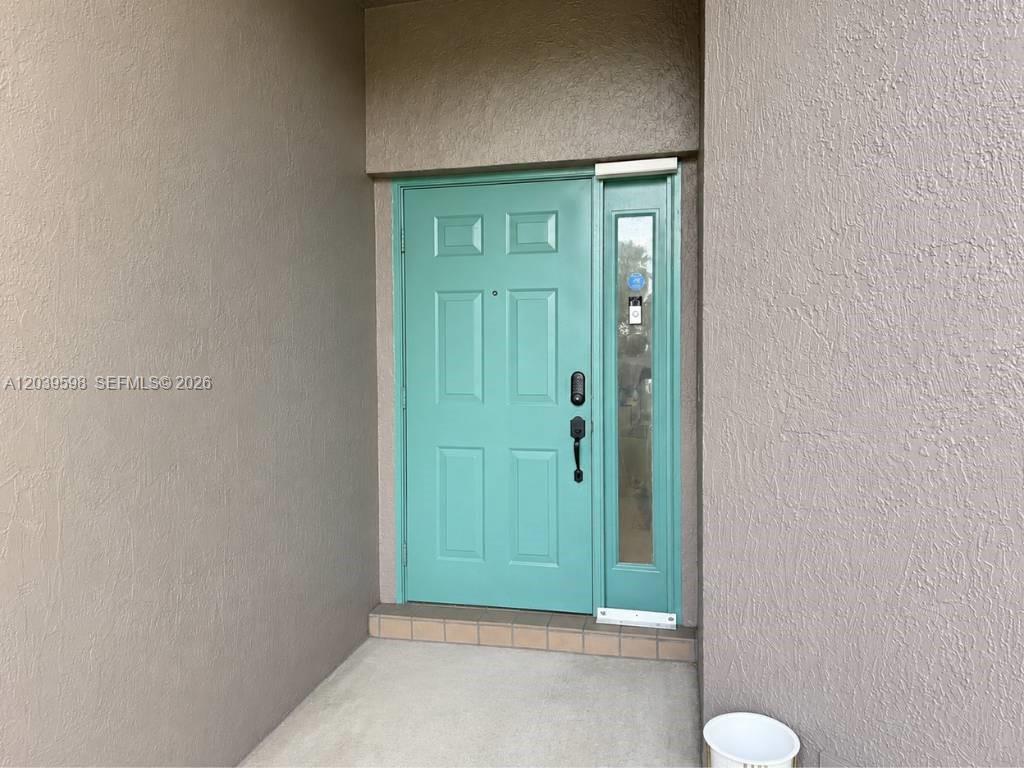 A teal front door with a side window is set into a tan stucco wall — 8090 S Aragon Blvd # 3, Sunrise FL 33322, SUNRISE, FL