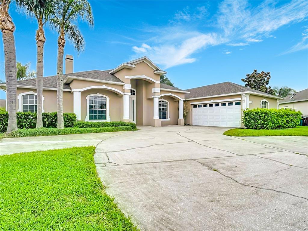 A tan single-story house with a white garage, arched windows, and palm trees in front — 3910 COUNTRYSIDE VIEW COURT, ST CLOUD, FL
