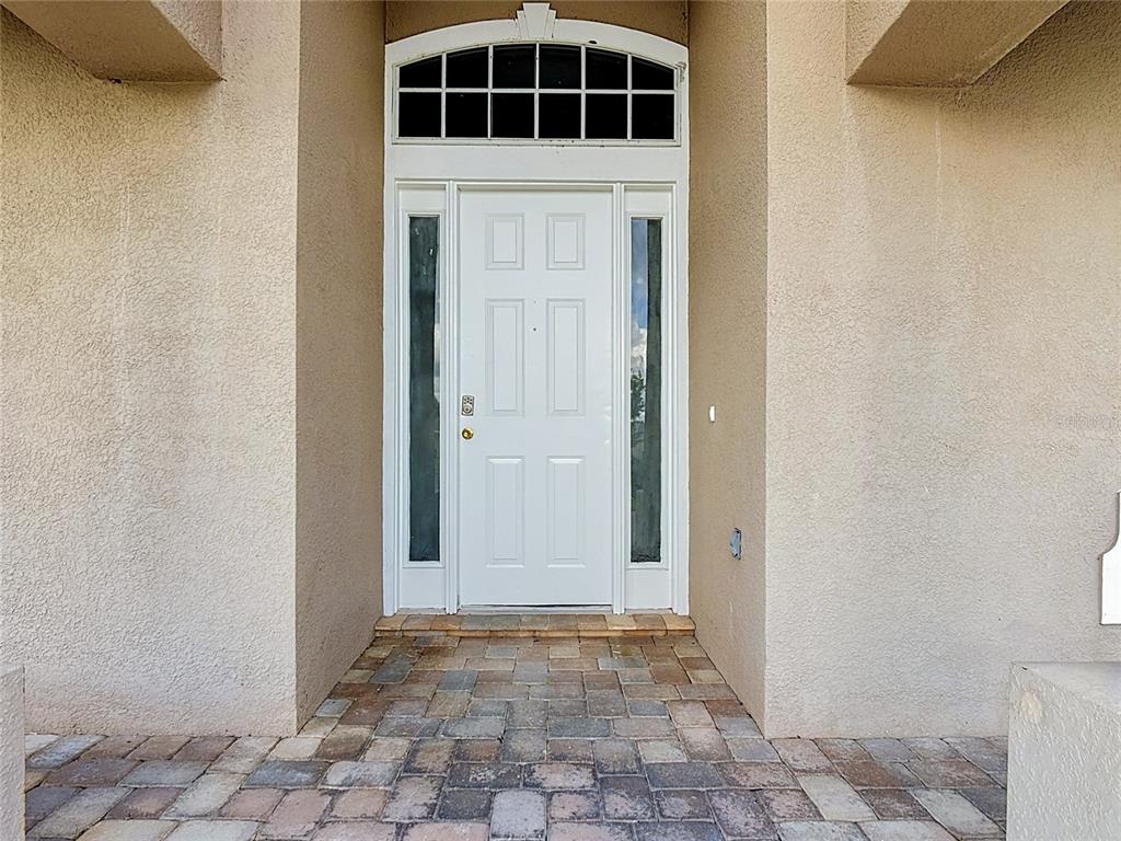 A white front door with sidelights and a transom window sits under a stucco entryway — 3910 COUNTRYSIDE VIEW COURT, ST CLOUD, FL