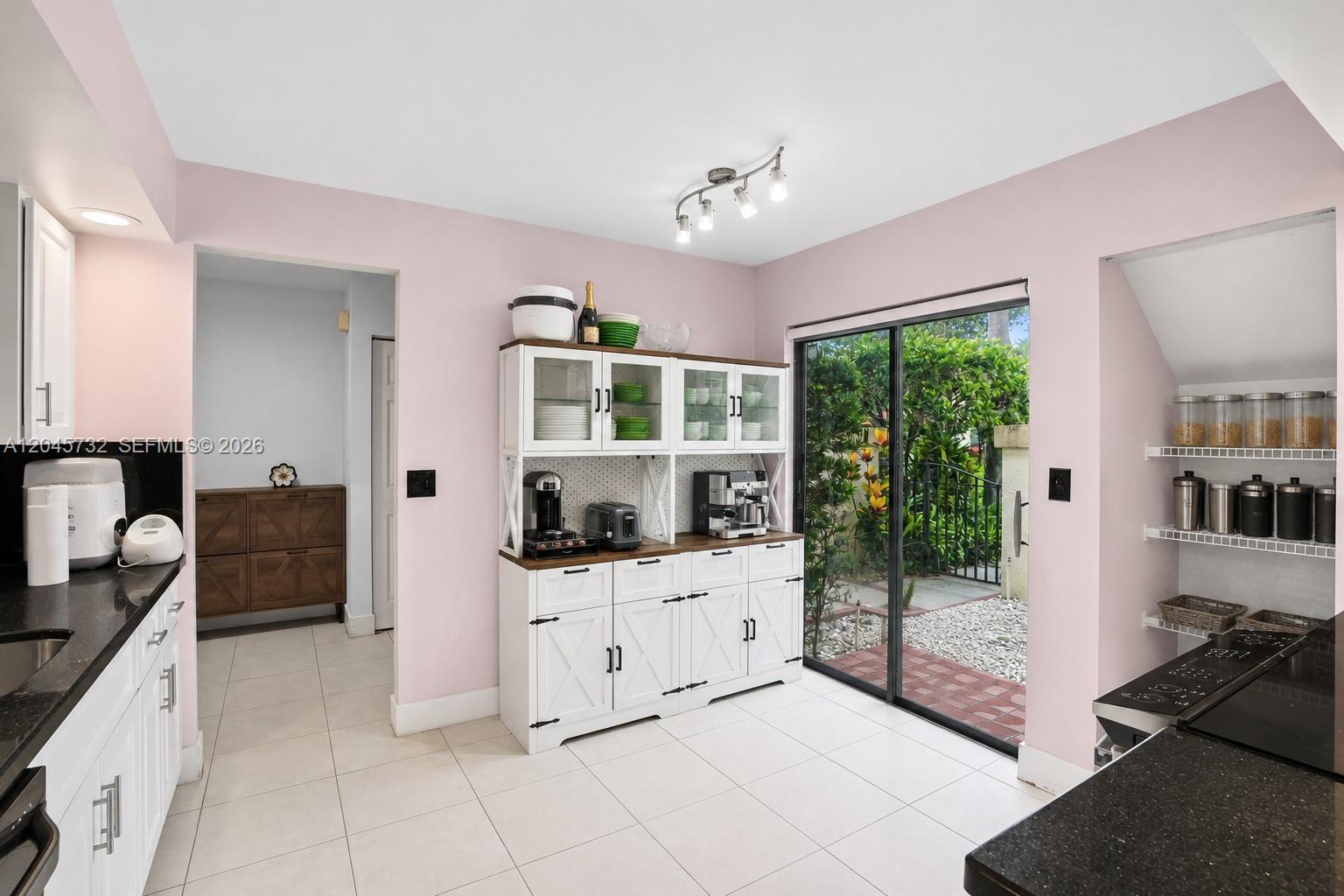 A kitchen features pink walls, white cabinetry, black countertops, and a sliding glass door — 7758 La Mirada Dr # 7758, Boca Raton FL 33433, BOCA RATON, FL