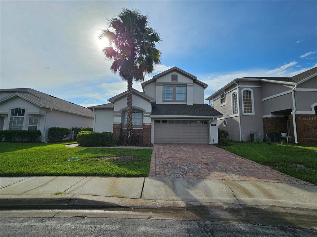 A two-story suburban house features a brick driveway, a palm tree, and a garage — 14321 MANDOLIN DR, ORLANDO, FL