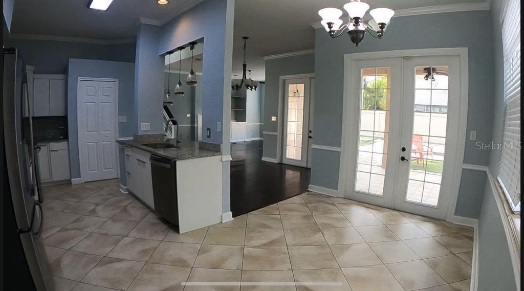 A kitchen with light blue walls, tile flooring, granite countertops, and a dining area — 14321 MANDOLIN DR, ORLANDO, FL