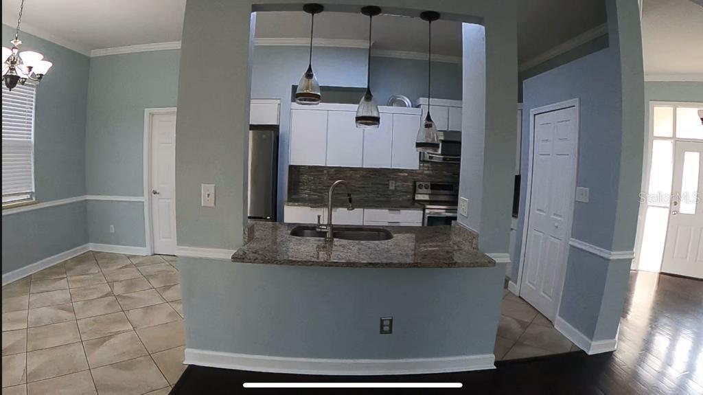 A kitchen with granite countertops and pendant lighting overlooks a dining area with tile floors — 14321 MANDOLIN DR, ORLANDO, FL