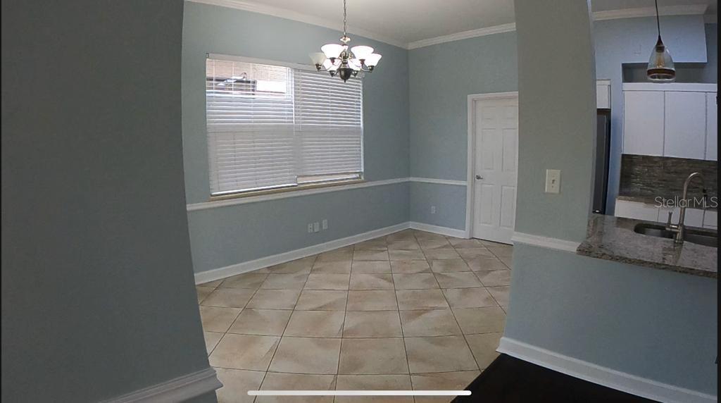 A dining area with light blue walls, tile flooring, a chandelier, and a large window — 14321 MANDOLIN DR, ORLANDO, FL