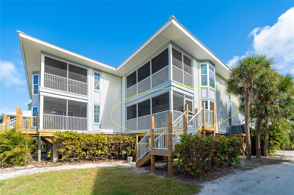 A two-story house with screened-in porches and a wooden staircase leading to the second level — 7446 PALM ISLAND DRIVE UNIT 3511, PLACIDA, FL