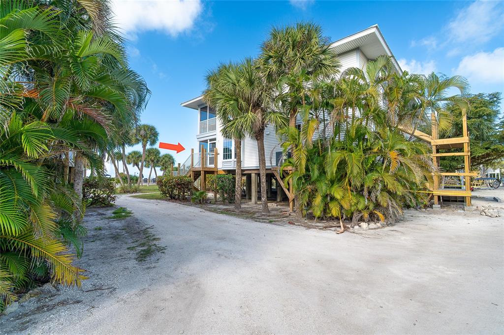 An elevated house with a wooden deck and staircase surrounded by palm trees — 7446 PALM ISLAND DRIVE UNIT 3511, PLACIDA, FL