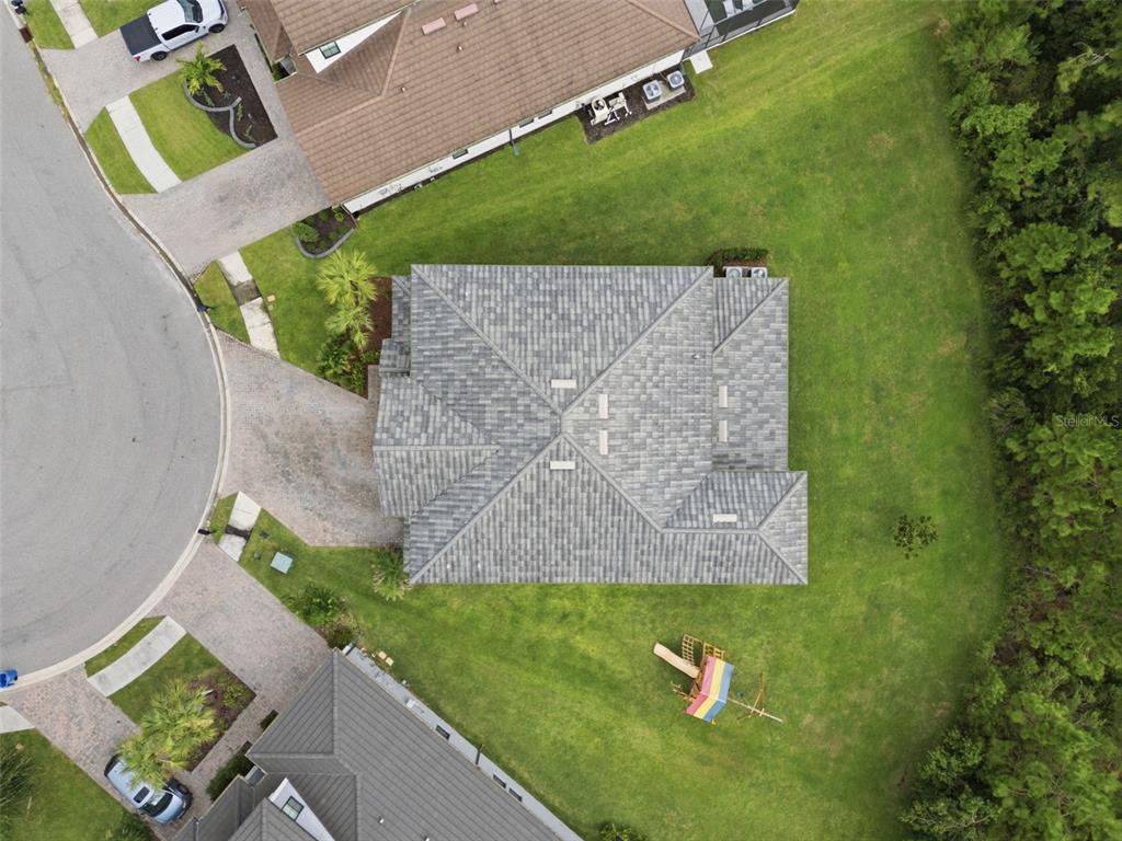 An aerial view shows a house with a gray shingled roof and a backyard playset — 4441 ALBERO PLACE, WESLEY CHAPEL, FL