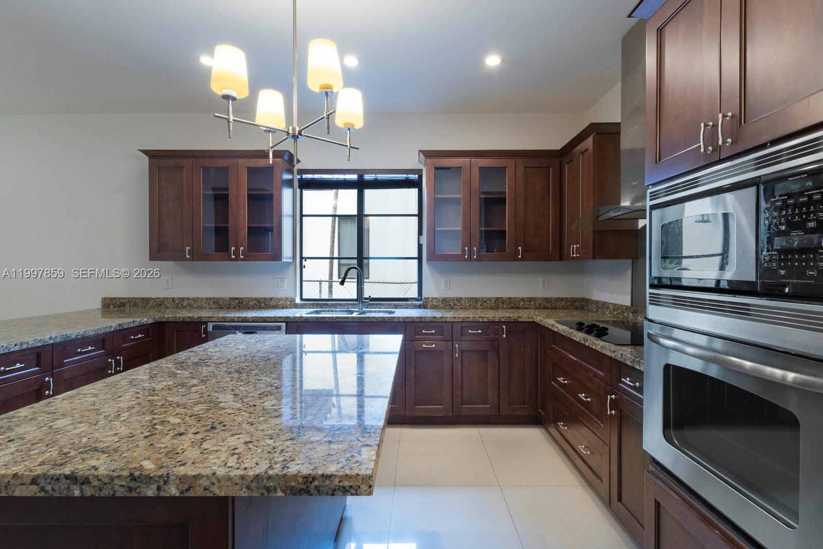 A kitchen features dark wood cabinets, granite countertops, a central island, and stainless steel appliances — 324 SW 30th Rd, Miami FL 33129, MIAMI, FL