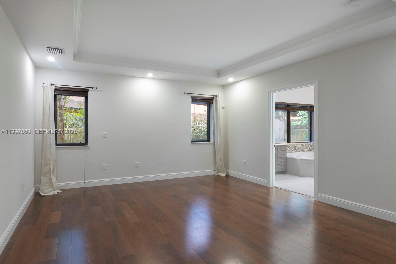 An empty bedroom features dark wood flooring, white walls, recessed lighting, and an attached bathroom — 324 SW 30th Rd, Miami FL 33129, MIAMI, FL