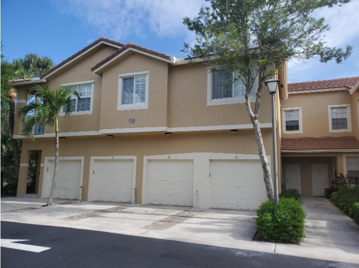 A two-story tan stucco building with four garage doors and a paved driveway — 158 Village Boulevard # D, Tequesta FL 33469, TEQUESTA, FL