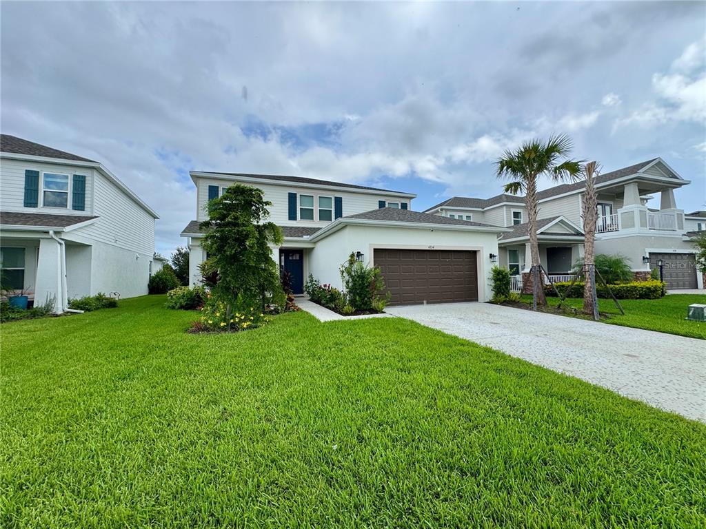 A two-story suburban house with a brown garage door and a green lawn — 4334 POND BROOK COURT, BRADENTON, FL