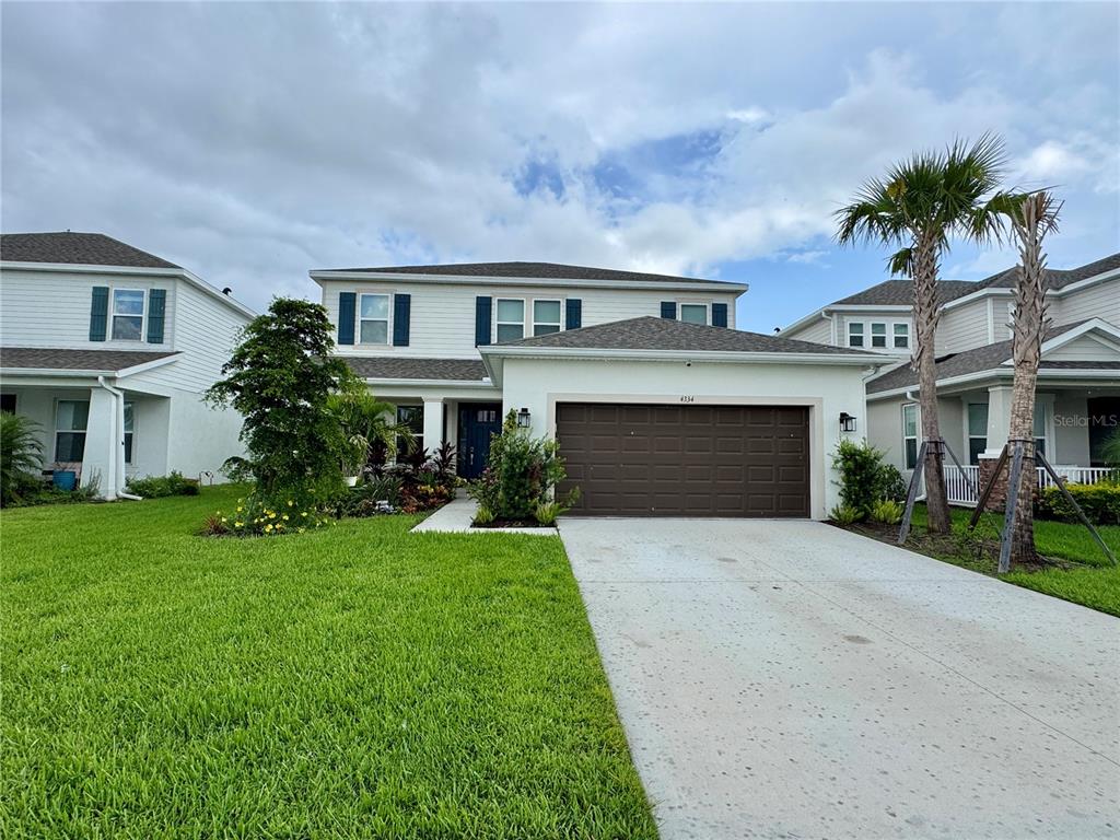 A two-story house with a white exterior, brown garage door, and a front lawn — 4334 POND BROOK COURT, BRADENTON, FL