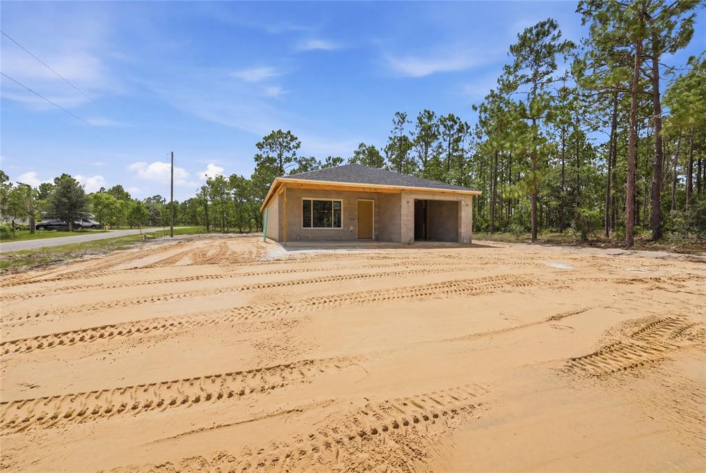 A newly constructed single-story house with an unfinished exterior stands on a sandy lot — 760 NE 149 COURT, WILLISTON, FL