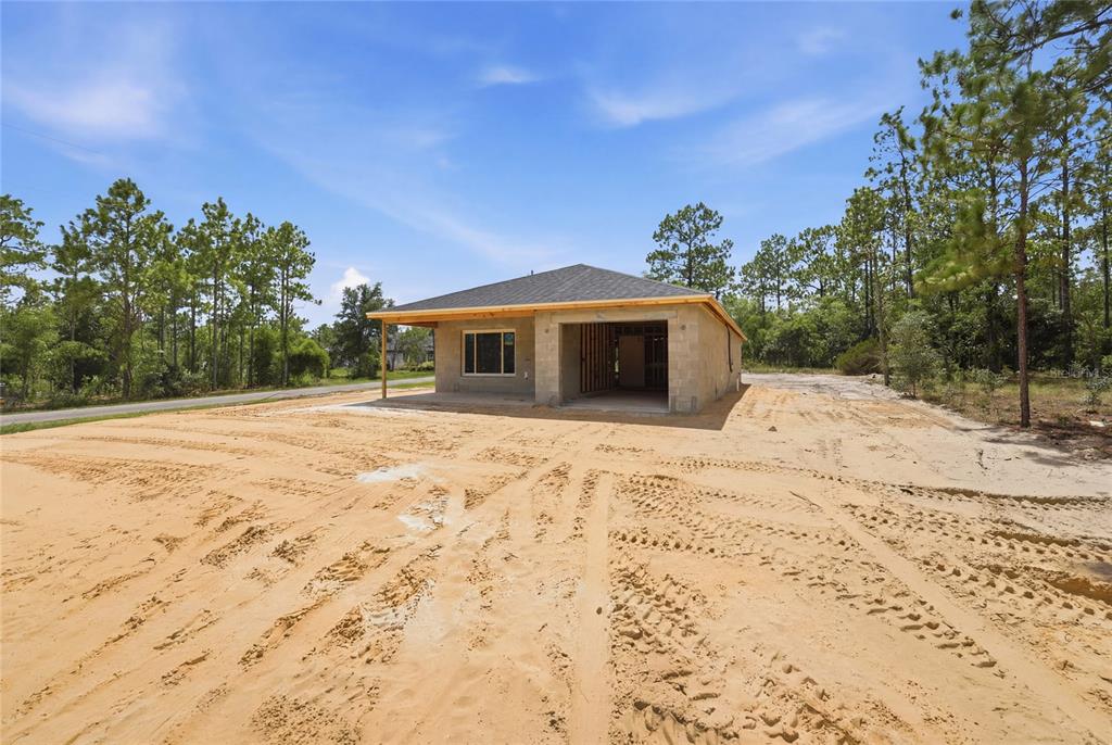 A single-story house under construction with an open garage and sandy lot — 760 NE 149 COURT, WILLISTON, FL