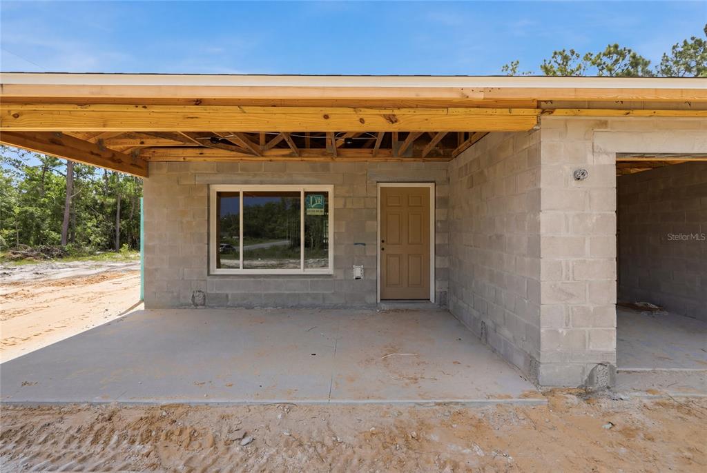 An unfinished concrete block house features a covered porch, a front door, and a window — 760 NE 149 COURT, WILLISTON, FL