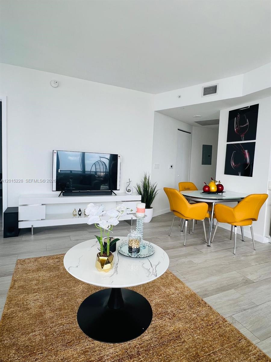 This living and dining area features white walls, light wood flooring, and yellow chairs — 55 SW 9th St # 3308, Miami FL 33130, MIAMI, FL