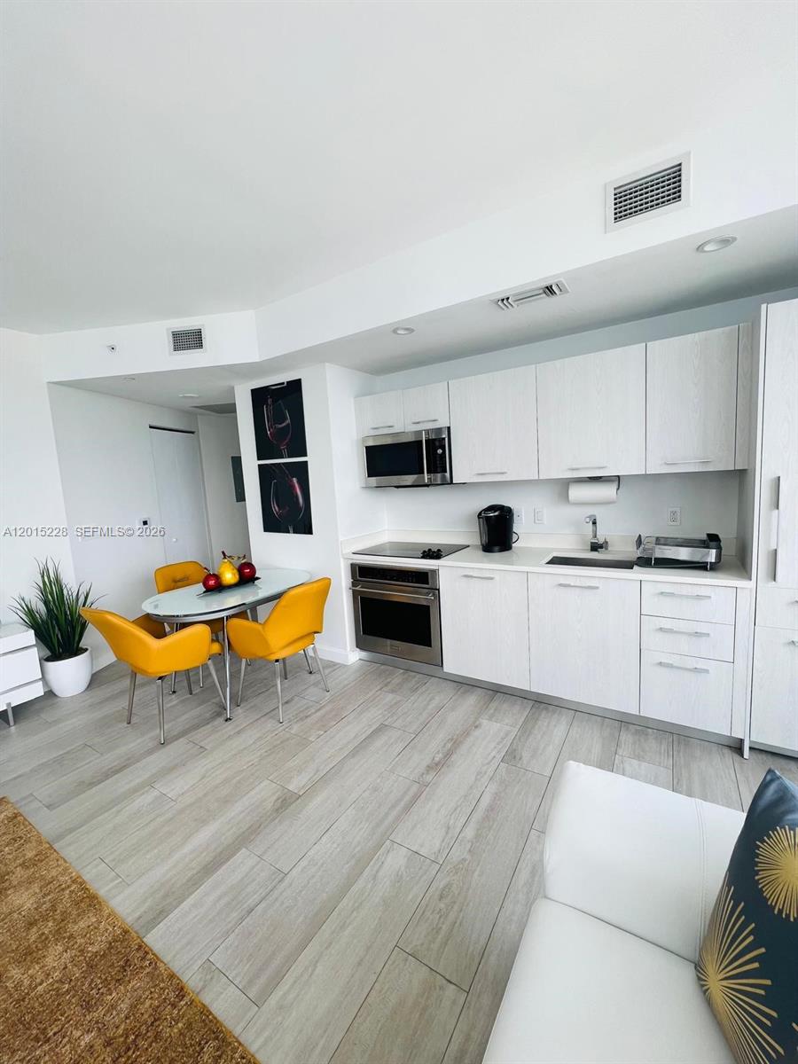 A kitchen with white cabinets and stainless steel appliances sits next to a dining area — 55 SW 9th St # 3308, Miami FL 33130, MIAMI, FL