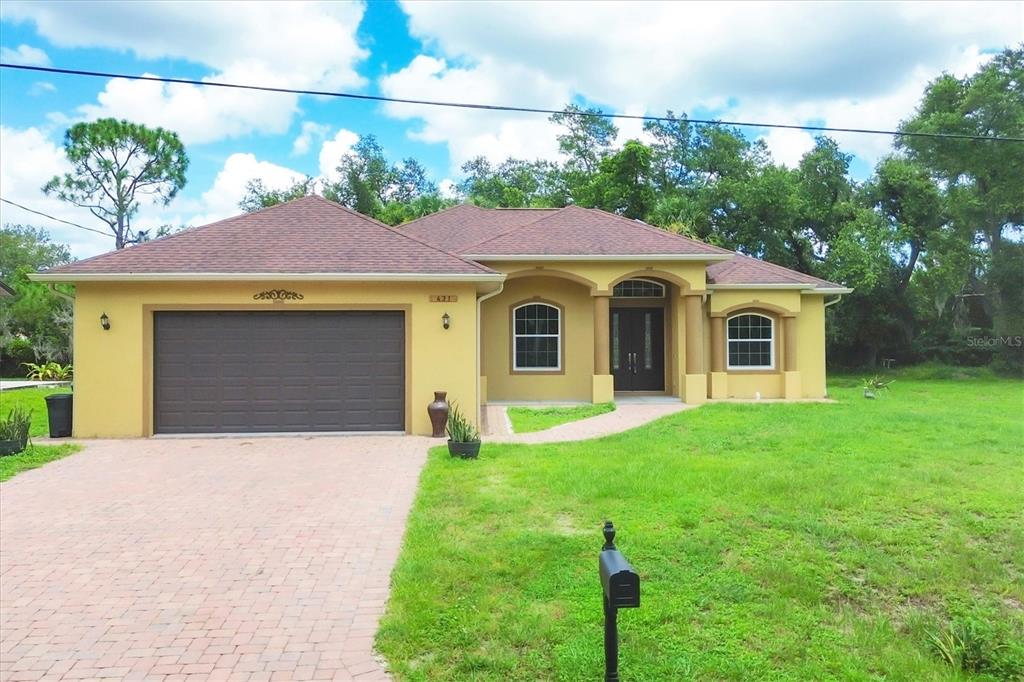 A single-story yellow house with a brown roof, a two-car garage, and a brick driveway — 431 SEVILLA STREET, NORTH PORT, FL