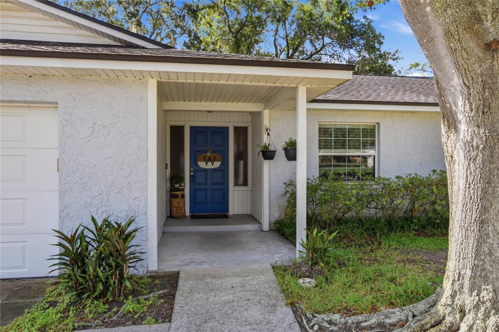 A white stucco house exterior features a blue front door and a covered entryway — 3028 WOOD SONG COURT, MULBERRY, FL